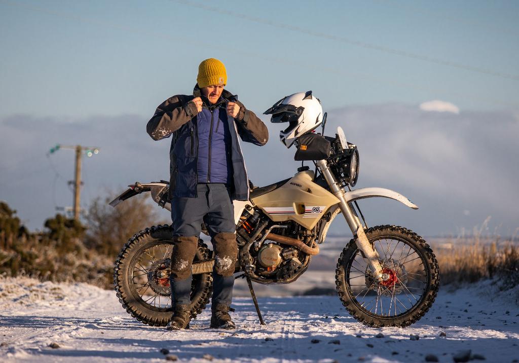 man putting singletrack jacket on with linesman pant adventure spec outdoor gear
